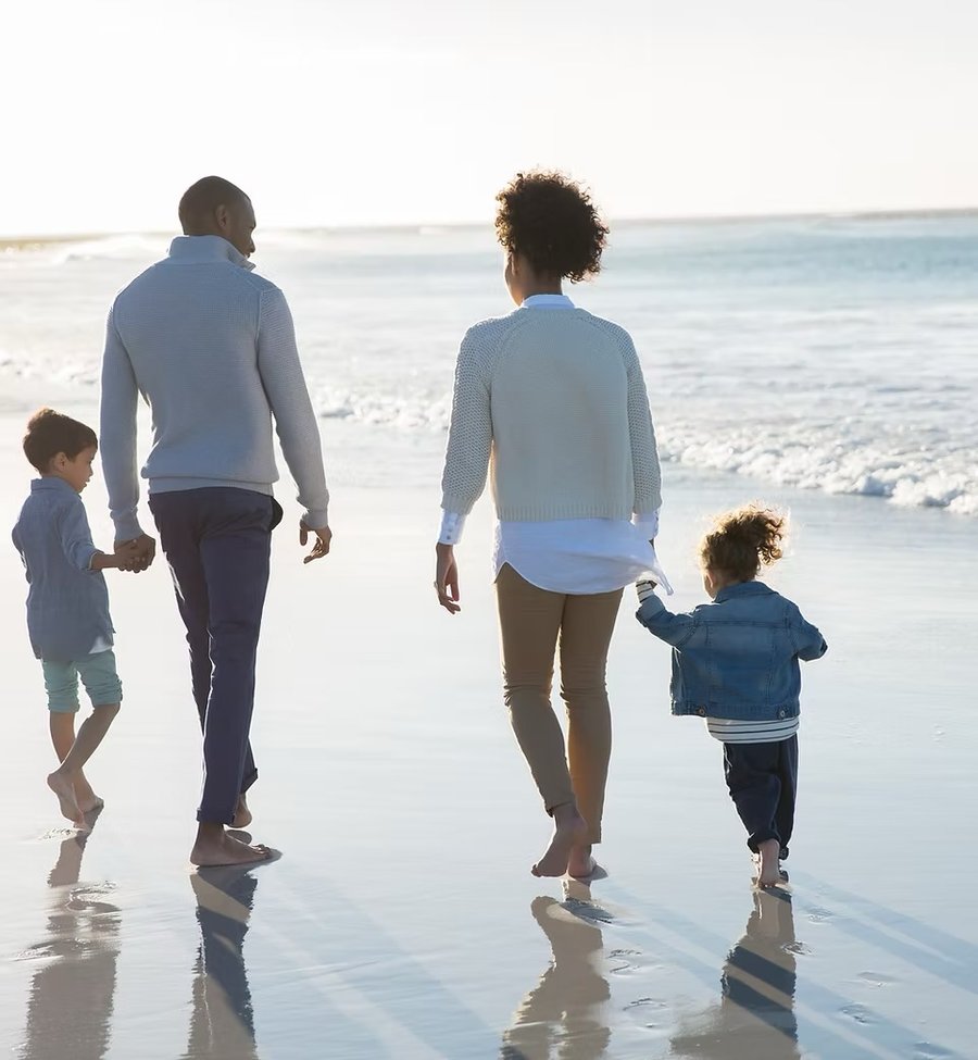 A family walking together along the shoreline at sunset